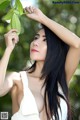 A woman in a white dress holding a green leaf.