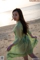 A woman in a green dress walking on the beach.